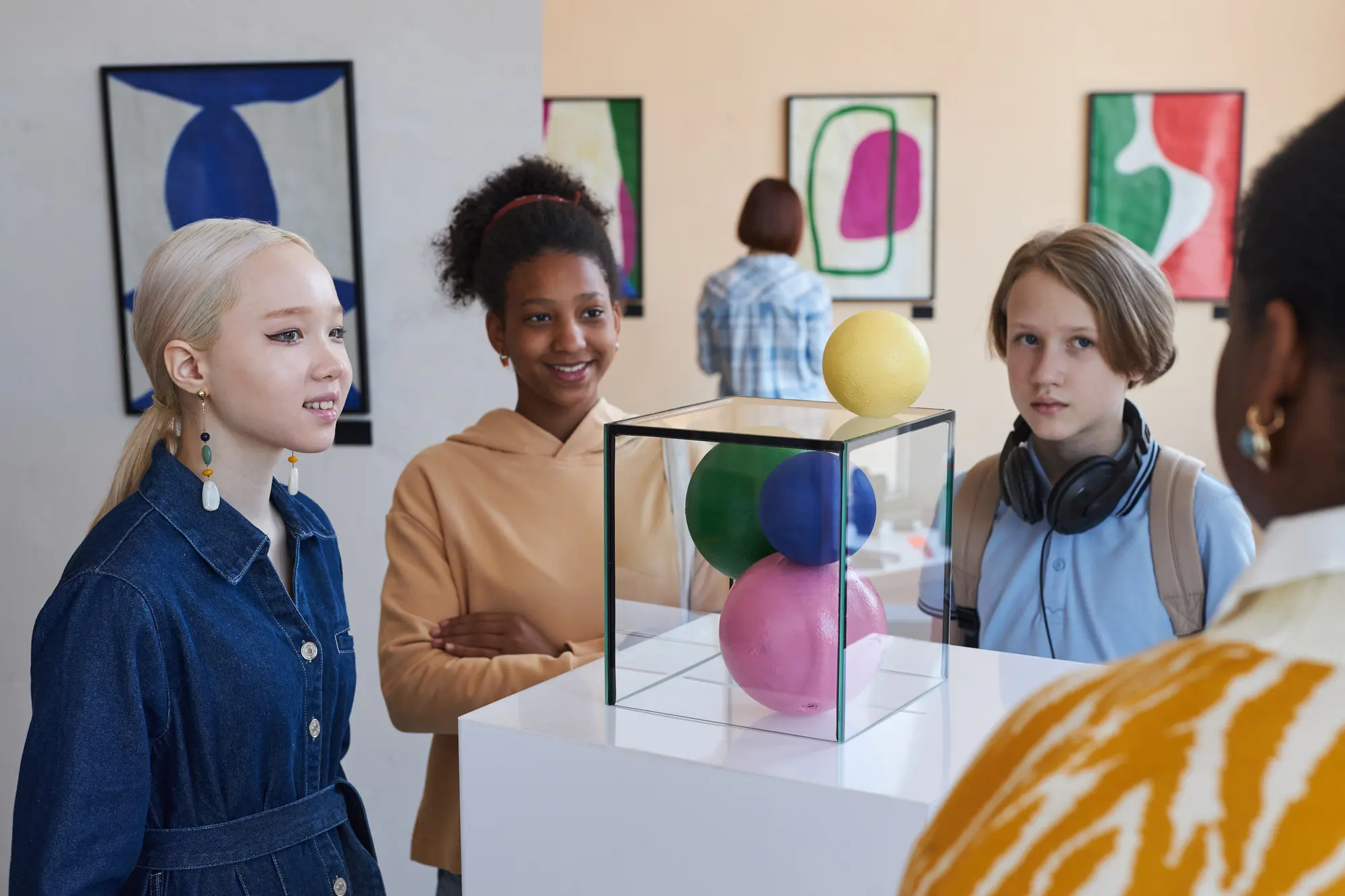 Un gruppo osserva una scultura di sfere colorate in una galleria