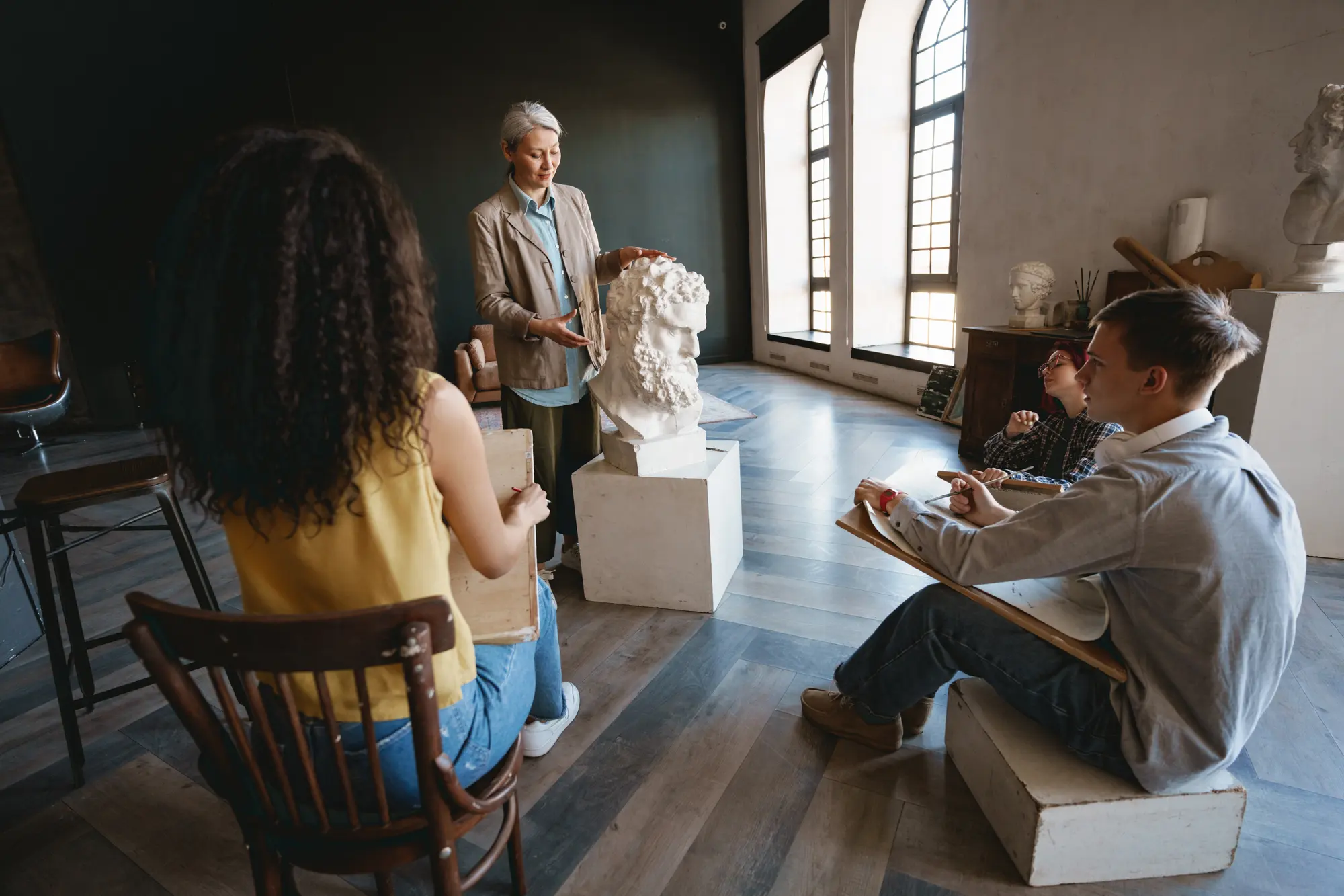 Un atelier con sculture classiche e persone che osservano e disegnano