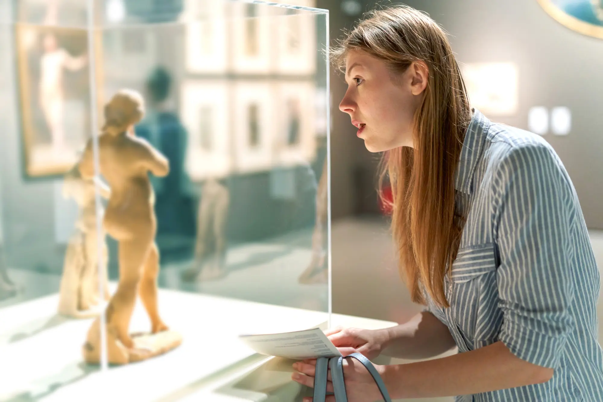 Una donna in un museo osserva da vicino una scultura