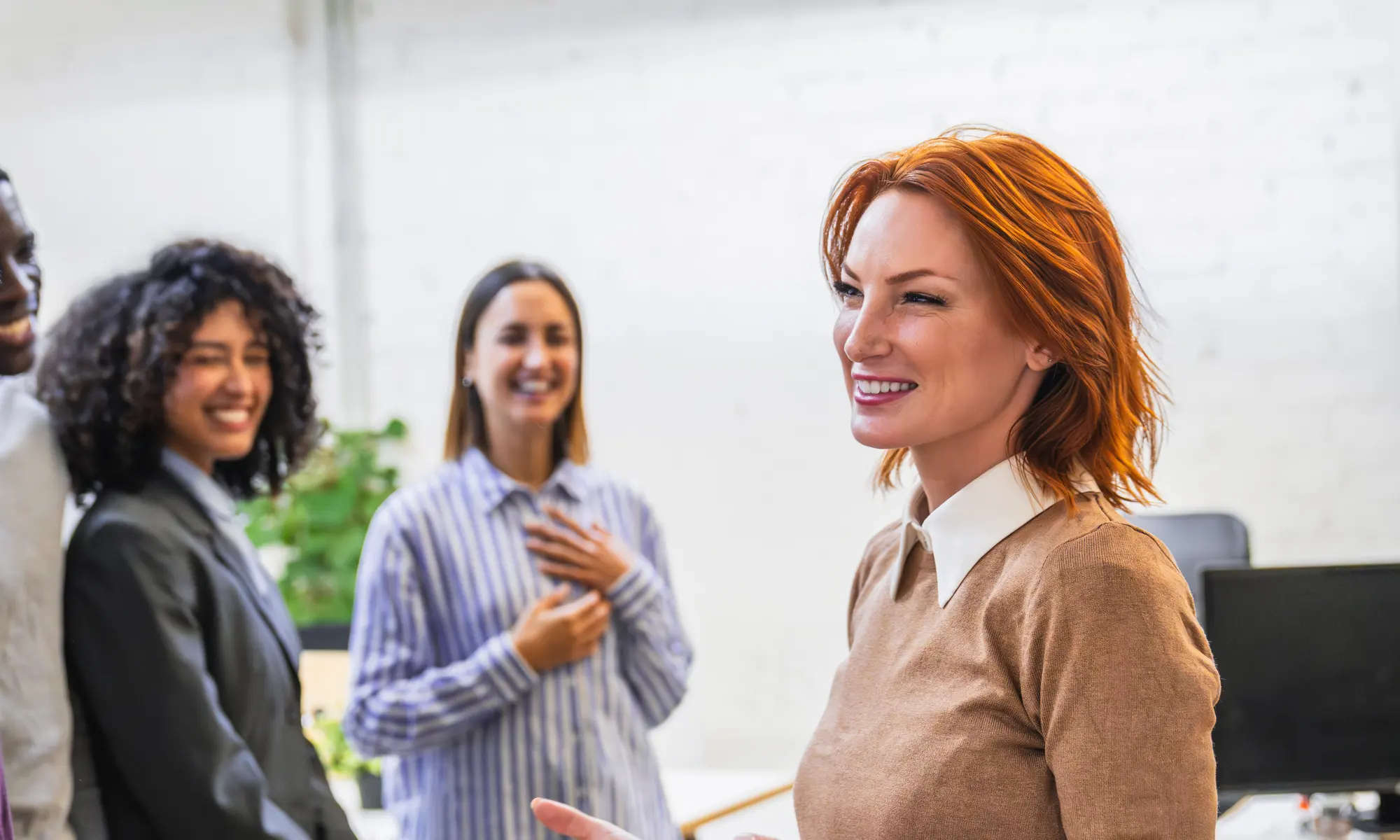Professioniste che conversano sorridenti in un ambiente di lavoro